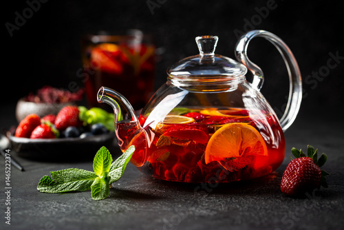 Obraz na płótnie Fruit red tea with berries in glass teapot on black background w salonie
