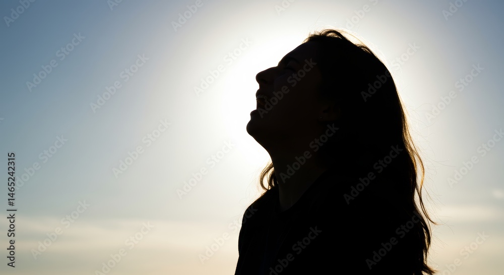 Fototapeta premium Silhouette of a Laughing Woman Against the Sky Expressing Joy and Freedom