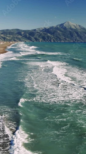 Turquoise waves breaking softly near sandy coast, mount athos rising majestically under summer sky, revealing tranquil mediterranean seascape with stunning natural beauty