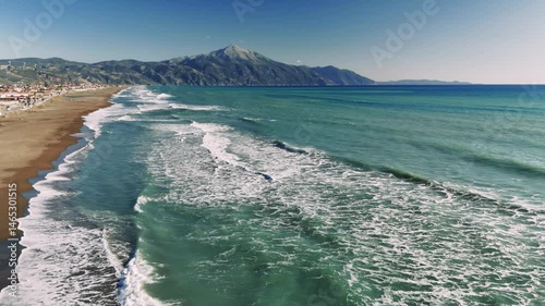Turquoise waves breaking softly near sandy coast, mount athos rising majestically under summer sky, revealing tranquil mediterranean seascape with stunning natural beauty