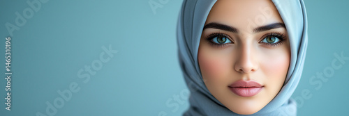 Arab businesswoman in hijab and business attire stands against blue background, Middle Eastern businesswoman, Muslim professional, confident expression, professional woman