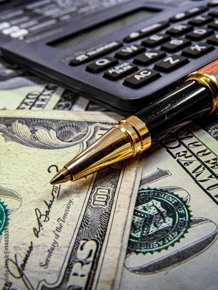 US Dollar money notes, pen and calculator on the table with narrow focus
