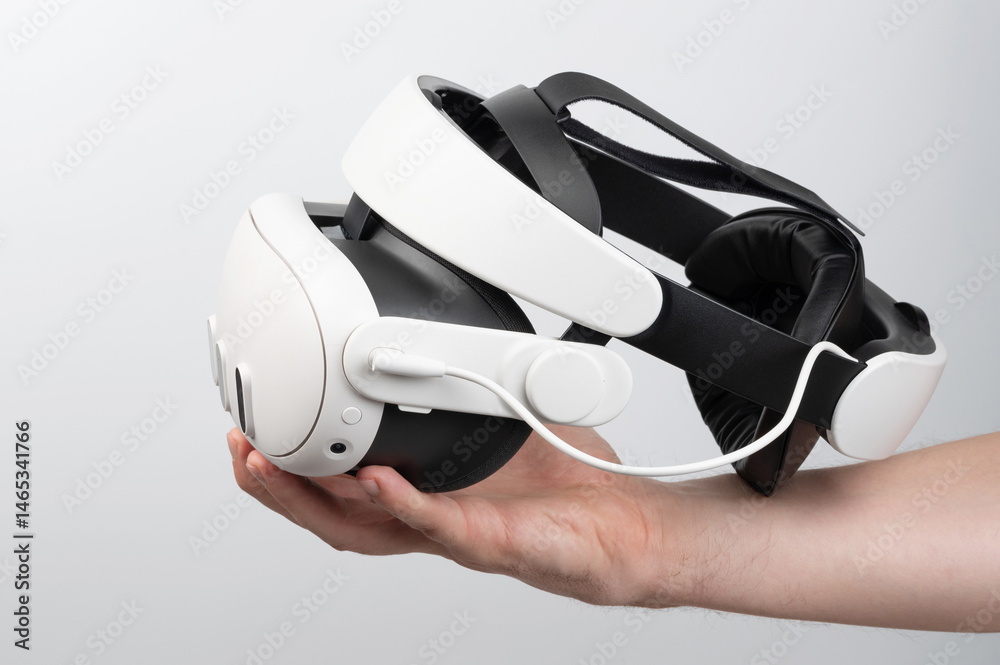 Hand holding VR headset against plain background, highlighting modern tech