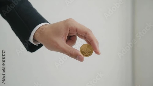 Businessman hand holding coin against plain background. Possible use stock photo for finance, business, or money concepts
