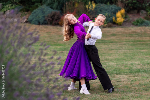 Elegant young boy and girl in ballroom dance attire performing outdoors. This juvenile dance couple captures grace, discipline, and youthful passion in a natural, outdoor setting. Ideal for themes rel
