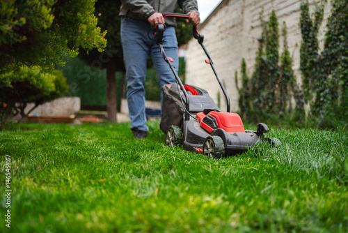 Canvas Print Person mowing a lush green lawn in a well-kept garden during a sunny afternoon i