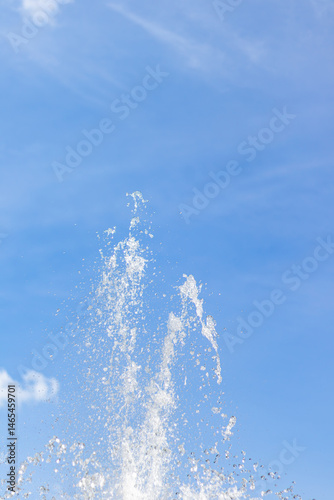High water jets of a fountain splashing upward against a bright blue sky.
