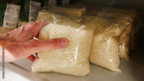 Close-up of a buyer's hand taking a rice packaging from a grocery store shelf