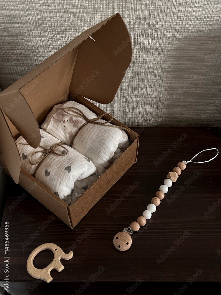 A box of muslin diapers, beads, and a wooden elephant teether are on the bedside table. Aesthetic minimalist baby fashion