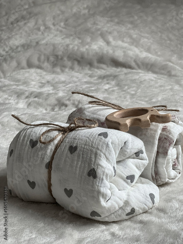 Obraz na płótnie Two twisted muslin diapers and an elephant teether are lying on a milky-colored blanket. Children's fashion accessories w salonie