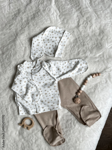 Obraz na płótnie Scandinavian style in children's fashion is a set of neutral beige children's clothes for discharge. Baby's turtleneck, pants, cap, elephant teether, beads on a white plaid. Top view w salonie