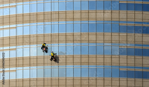 high rise building Window washers cleaning the glass facade of a modern building, skyscraper high risk work.