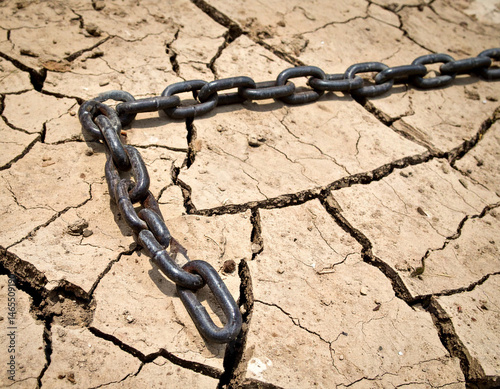 A broken chain lying on cracked earth symbolizing the breaking of violence. photo