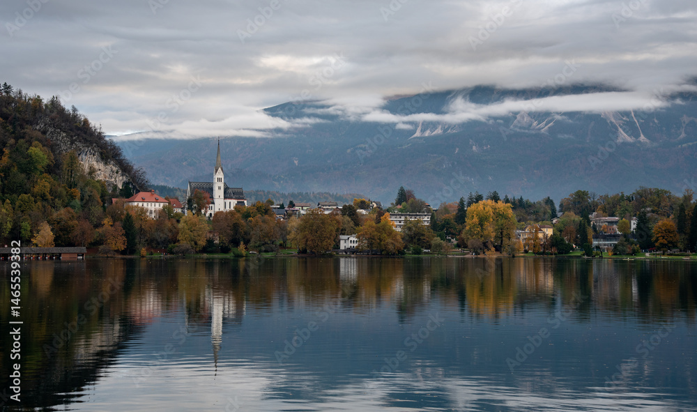 Assumption of mary pilgrimage church on lake bled, surrounded by mountains and colorful autumn foliage, Slovenia