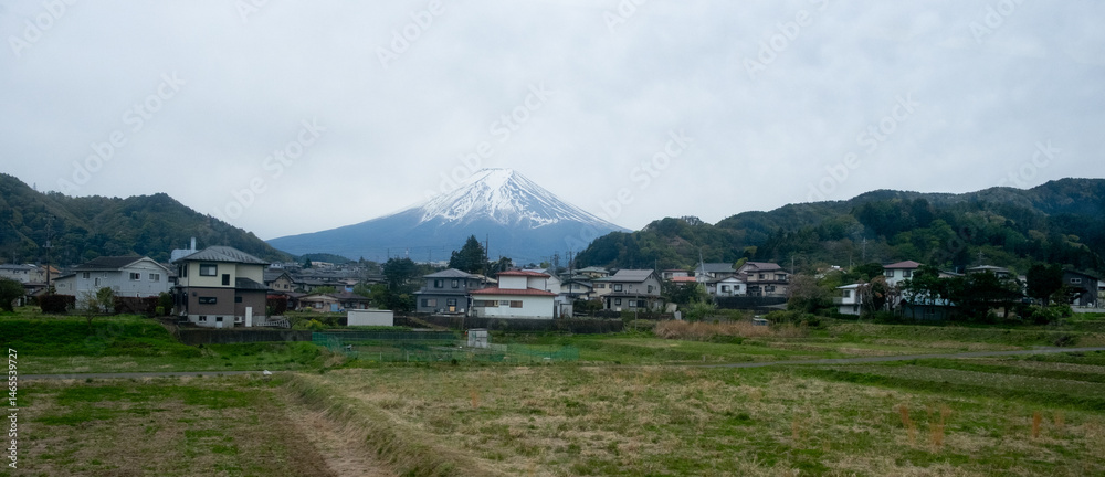 Mount fuji dominating the skyline over a residential area and cultivated fields in japan