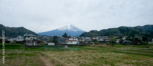 Obraz na płótnie Mount fuji dominating the skyline over a residential area and cultivated fields in japan w salonie