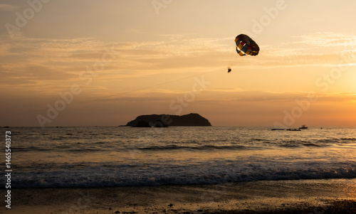 Sunset parasailing adventure over the ocean near a coastal island