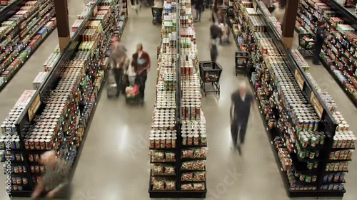 Overhead View Of Busy Supermarket Interior With Shoppers Walking Along Aisles