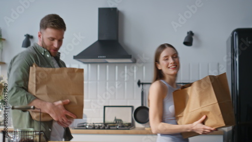 Obraz na płótnie Family couple unpacking groceries in white kitchen closeup. Happy man and woman w salonie