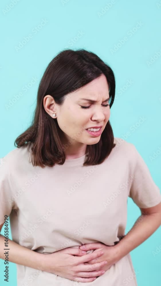 Woman suffering from abdominal pain on turquoise background Woman suffering from abdominal pain on turquoise background