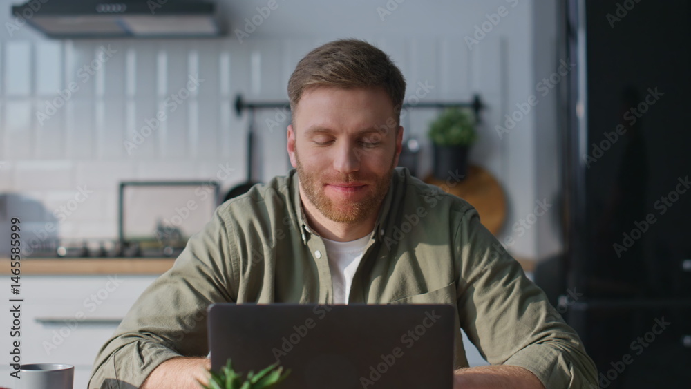 Smiling man video calling laptop in home kitchen closeup. Happy freelancer work