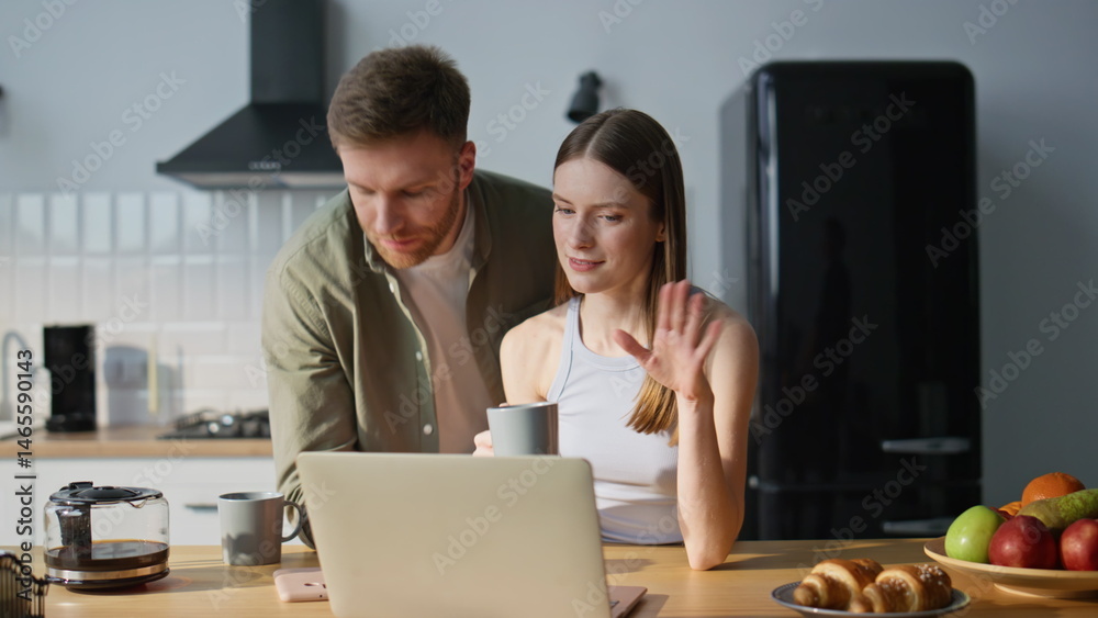 Smiling spouses looking laptop in kitchen enjoying morning together closeup.