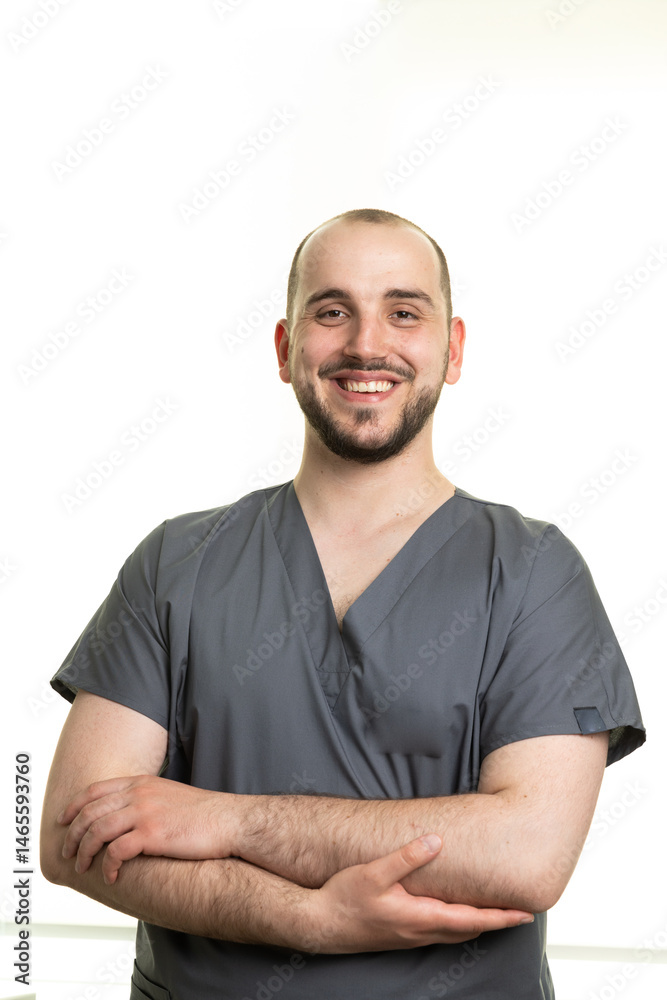 Fototapeta premium Smiling Male Medical Professional in Scrubs Posing with Confident Posture and Friendly Expression in Bright, Minimalist Environment