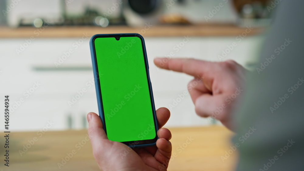 Hand pointing smartphone green screen browsing application in apartment closeup.