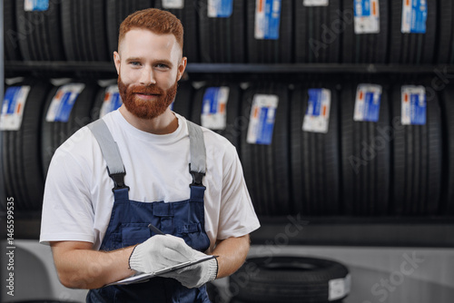 Obraz na płótnie Car tire service concept. Portrait man mechanic salesman holding tablet on new tyre store background w salonie