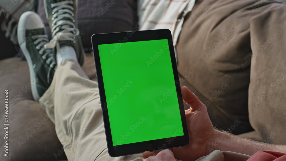 Student watching greenscreen tablet webinar on couch closeup. Man browsing home