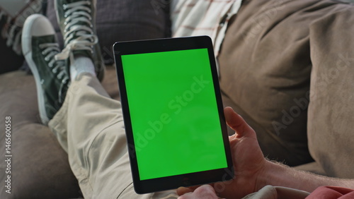 Obraz na płótnie Student watching greenscreen tablet webinar on couch closeup. Man browsing home w salonie