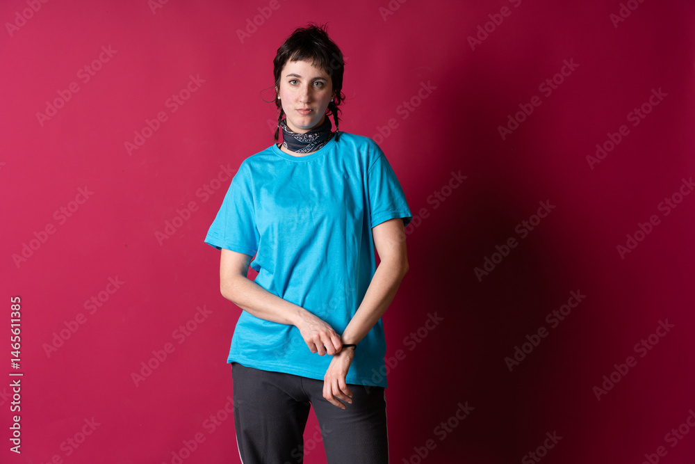 Young woman wearing blue t-shirt and fixing her wristband on crimson background Young woman wearing blue t-shirt and fixing her wristband on crimson background