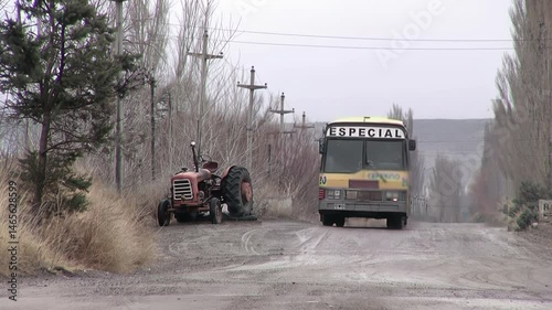 Old School Bus on Muddy Rural Road Passing a Tractor in Patagonia, Argentina - 4K