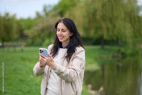 Smiling woman making a video call in park and pointing upward