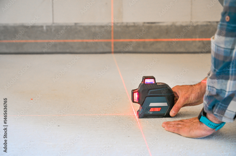 A person using a laser level tool on a smooth surface to ensure accurate measurements, showcasing the practicality of technology in construction and home improvement projects
