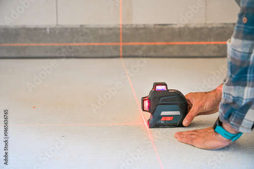 A person using a laser level tool on a smooth surface to ensure accurate measurements, showcasing the practicality of technology in construction and home improvement projects