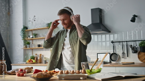 Obraz na płótnie Smiling man chopping vegetables in kitchen dancing with headphones closeup. w salonie
