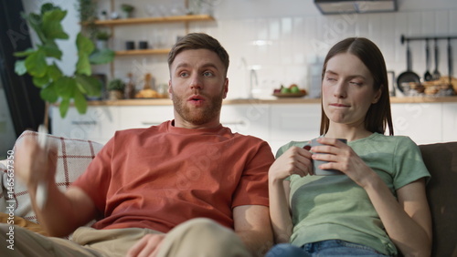 Family couple watching TV together at home sofa closeup. Emotional wife husband 