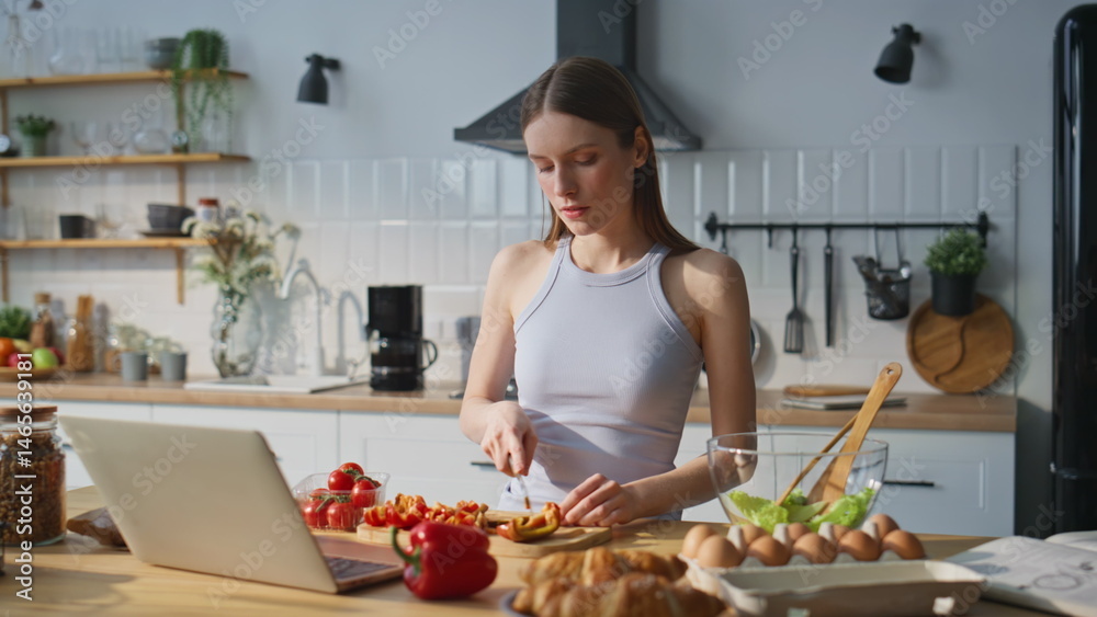 Woman watching online recipe chopping fresh vegetables in kitchen home closeup.