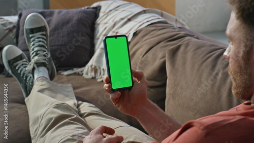 Obraz na płótnie Guy browsing greenscreen cellphone relaxing on couch home closeup. Relaxed man w salonie
