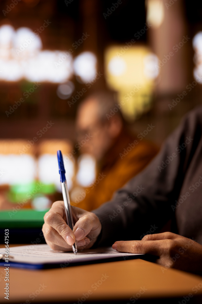 Mature academic person prepares documents for her university coursework, transcribing from literature and textbooks. Scholar focused on research and education in a public library. Close up.