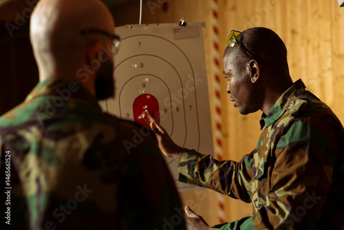 Army soldiers at shooting gallery participate in elite level marksmanship training program, hitting targets, comparing results. Military units at firing range doing shooting course, shooting bullseyes
