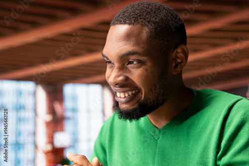 Obraz na płótnie Joyous happy african american man in apartment smiling, looking pleased, enjoying leisure time. Jolly upbeat person sitting at home desk exulting, feeling satisfied, close up shot w salonie