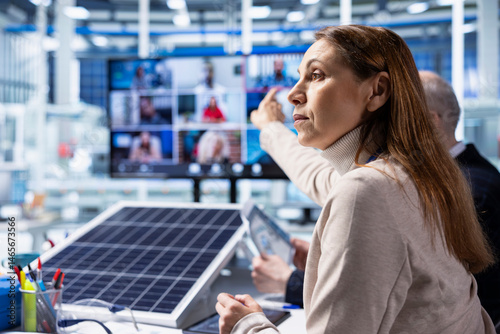 Solar panels factory investors evaluate investment profitability during teleconference meeting. Photovoltaics plant executives analyzing green energy manufacturing machinery during internet videocall