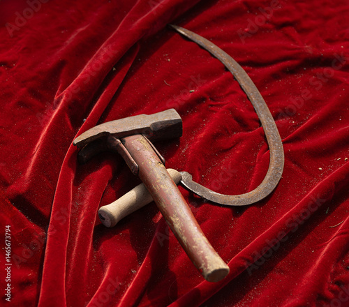 Closeup of a vintage hammer and sickle dark red velvet fabric. The tools, historically symbolic of communism and Soviet ideology
