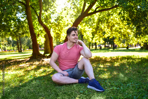 Happy Young Man Looking Away Sitting in Sunny Park
