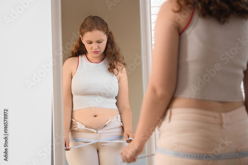 Young woman measuring waist...