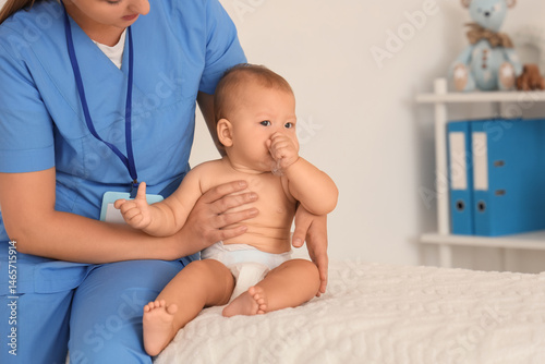 Pediatrician holding infant baby during medical examination, child health car...