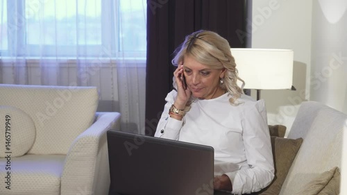 Businesswoman joyfully taking a call while working on her laptop