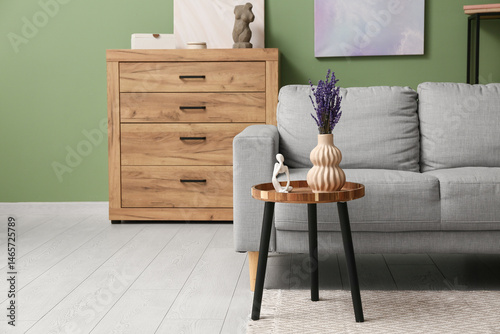 Vase with beautiful lavender flowers and decor on wooden table in stylish living room